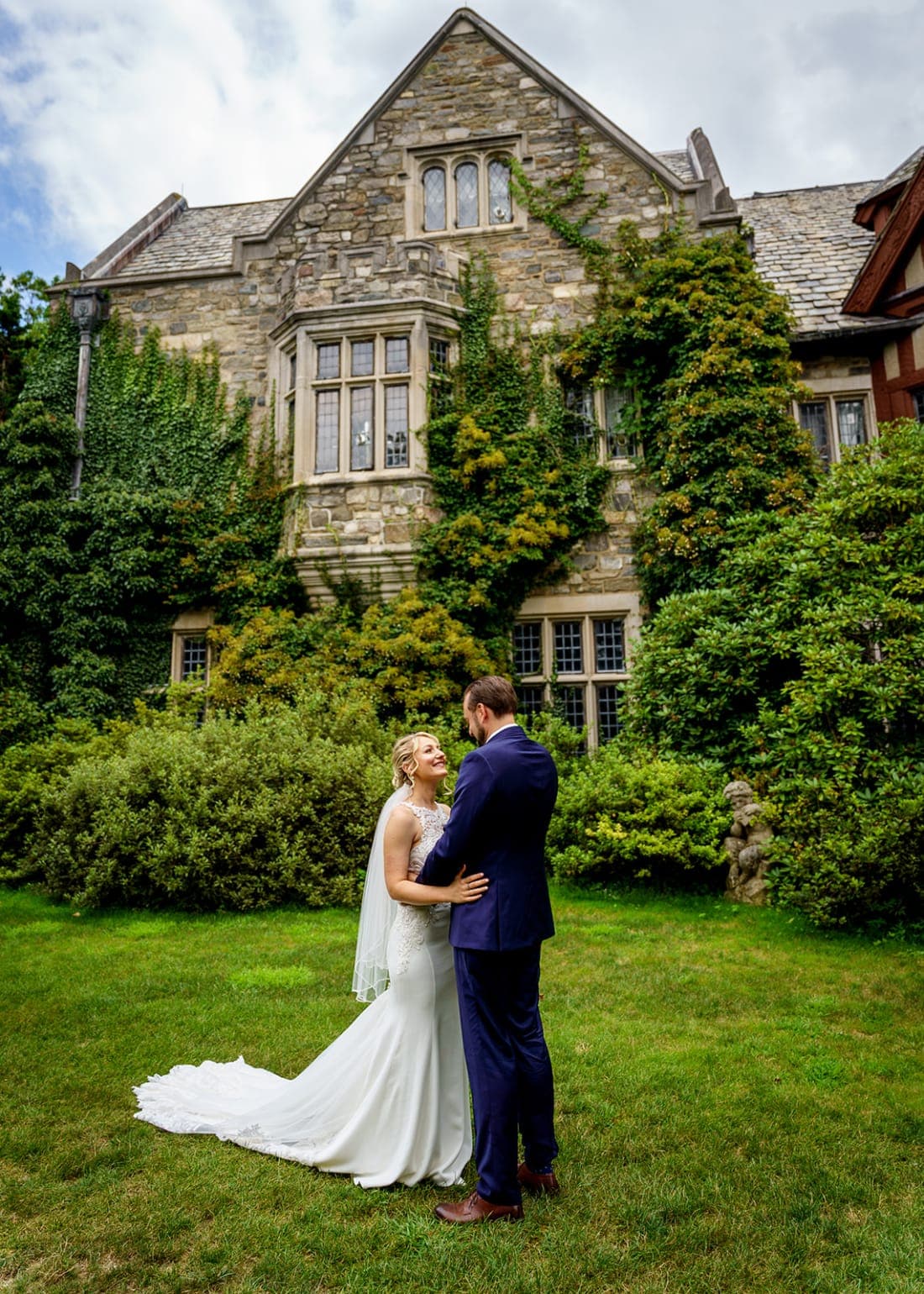 Crysta and David on the lawn in front of the ivy-covered stone manor at Skylands Manor