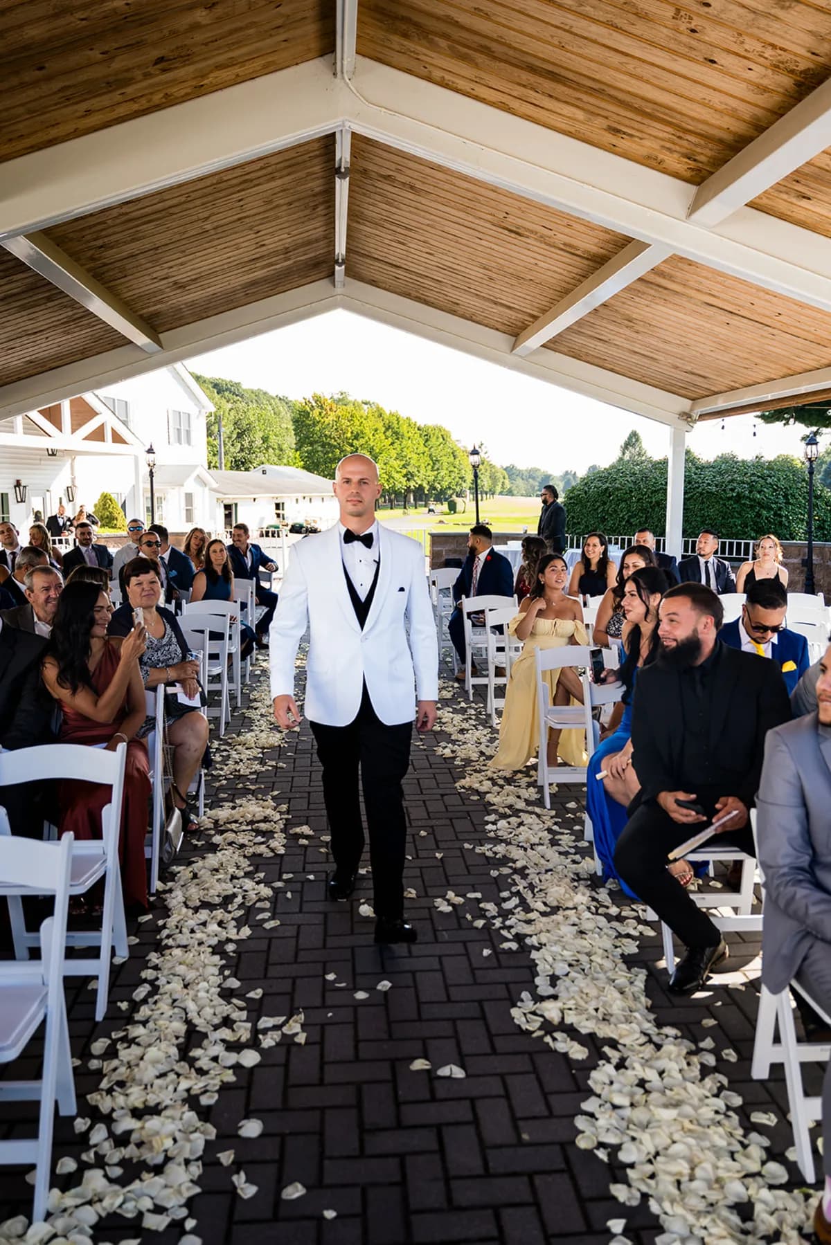 Groom walking down the aisle under the covered pergola at The Club at Picatinny
