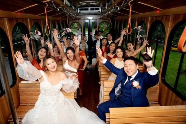 Amanda, Alex and their wedding party cheering inside a wood-panelled trolley