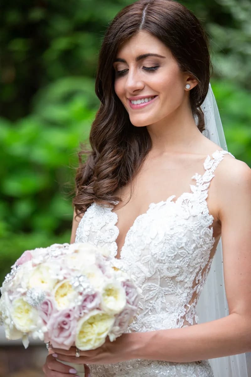 Karni smiling down at her bouquet in the garden at The Venetian