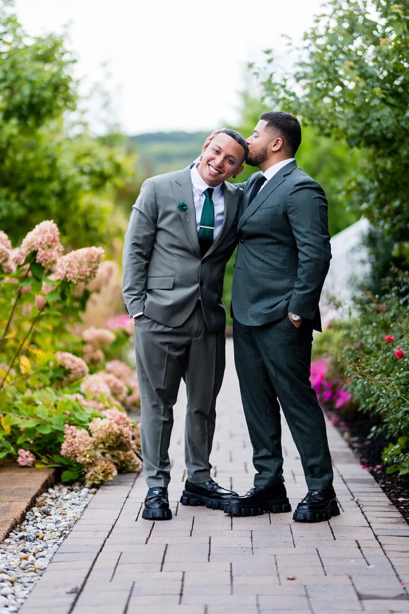 Jose and a groomsman sharing a laugh on a garden path at The Meadow Wood