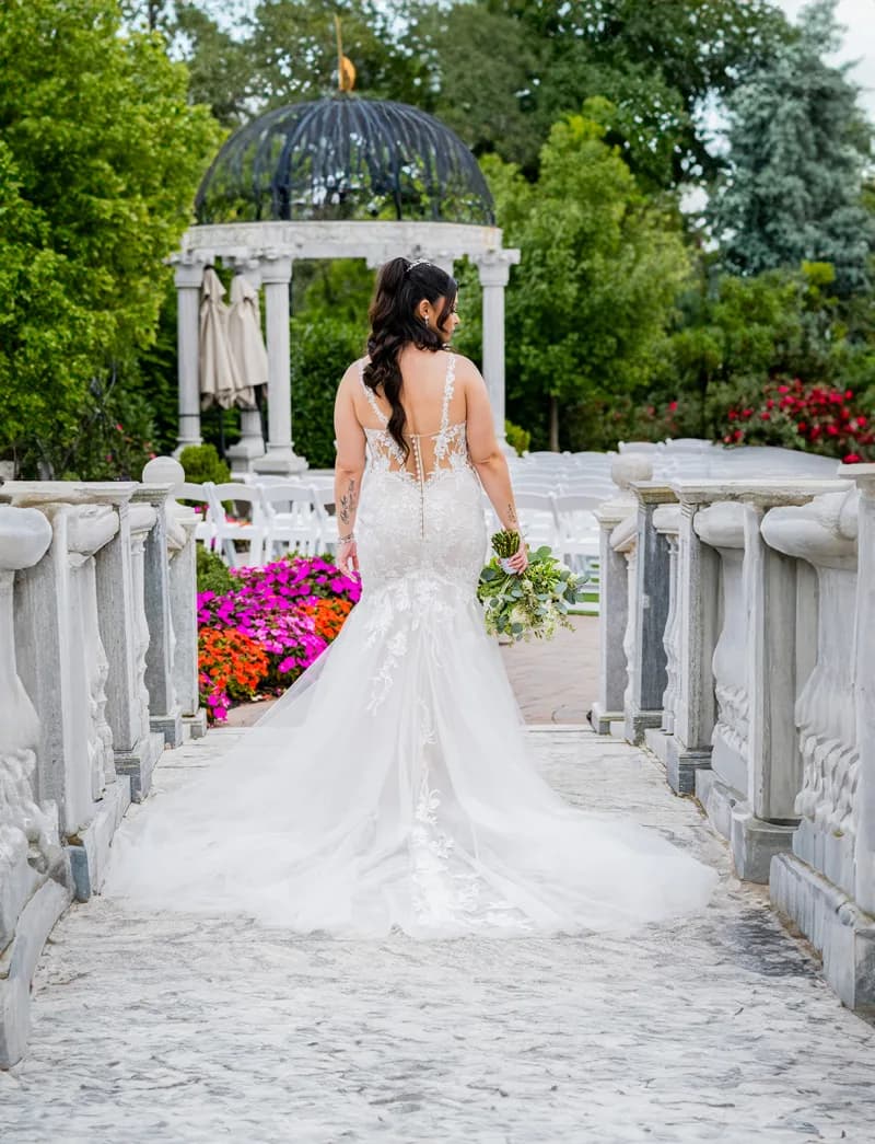 Anna walking a balustraded path toward the ceremony gazebo and seated guests at The Meadow Wood