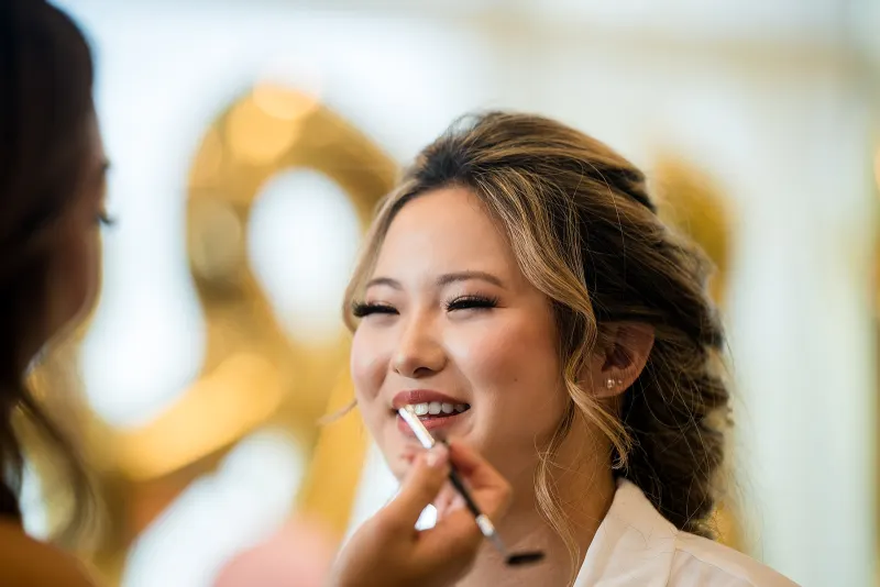 Amanda laughing while her makeup is finished on the morning of the wedding